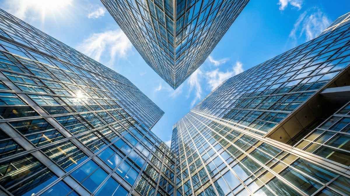 Low angle view of converging glass skyscrapers representing the structural complexity of modern business.