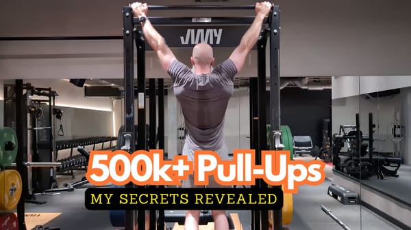 Rear view of Phil Jessé performing a wide-grip pull-up in a gym, demonstrating the lat engagement required for endurance training.